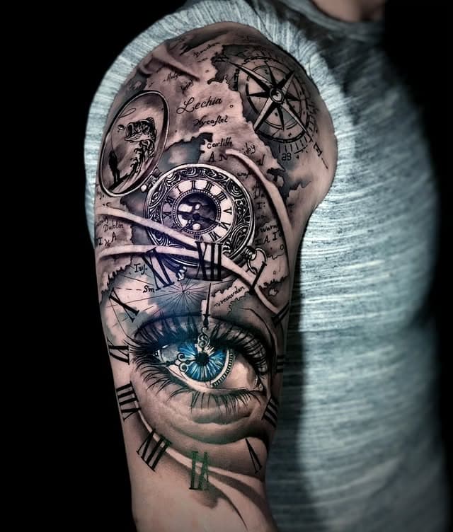 Realistische tattoo van een blauw oog, kompas, klok en oude kaart op de bovenarm.