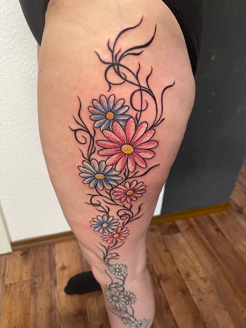 Kleurrijke bloemenrank met madeliefjes op het bovenbeen.