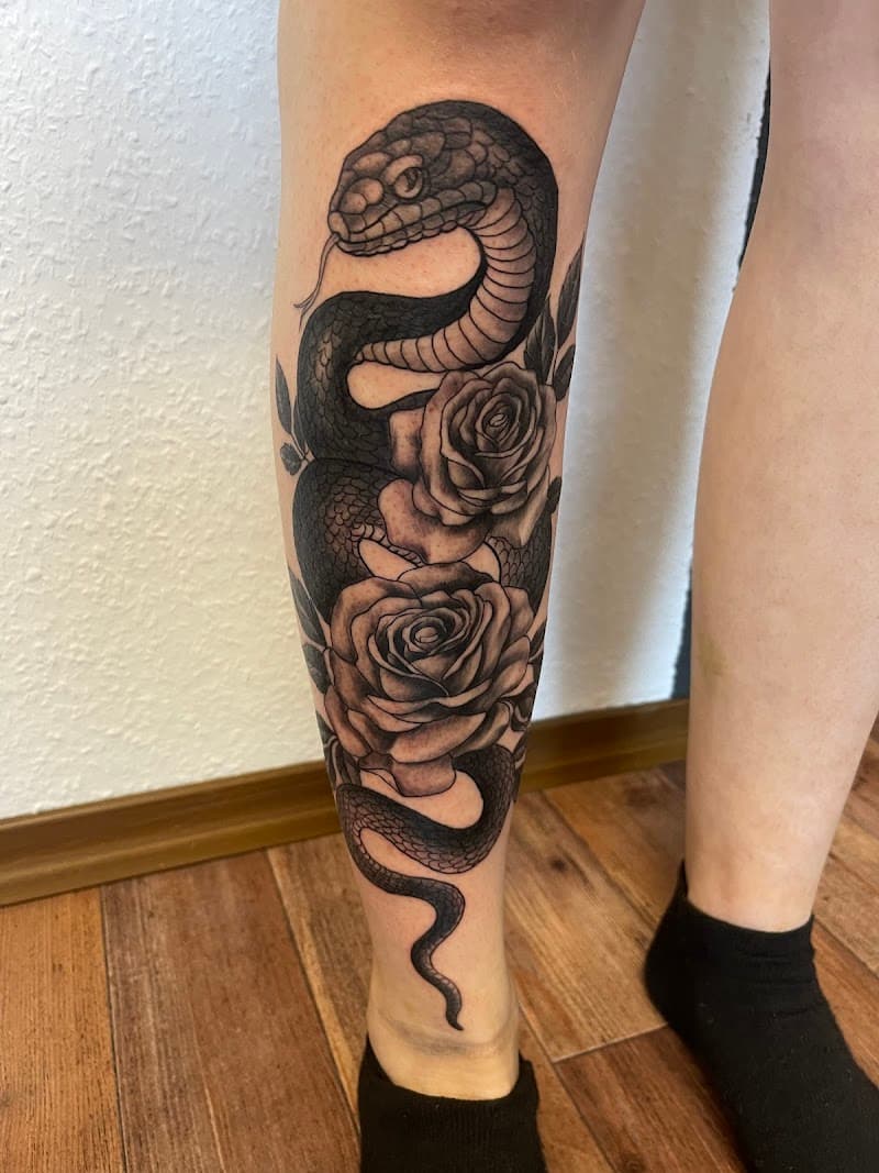 Blackwork slang en rozen op onderbeen.