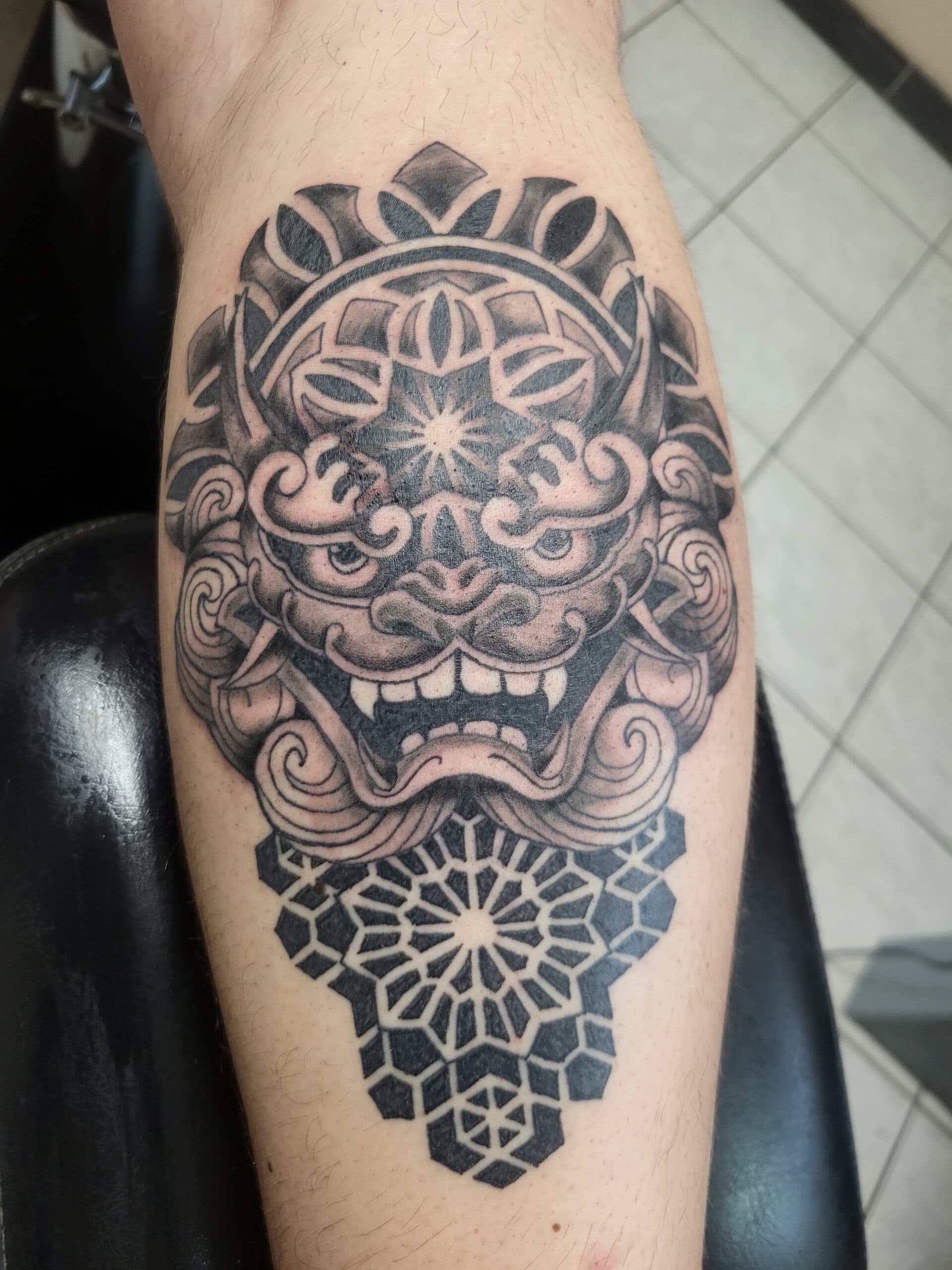 Blackwork Foo Dog kop met geometrische patronen op het onderbeen.