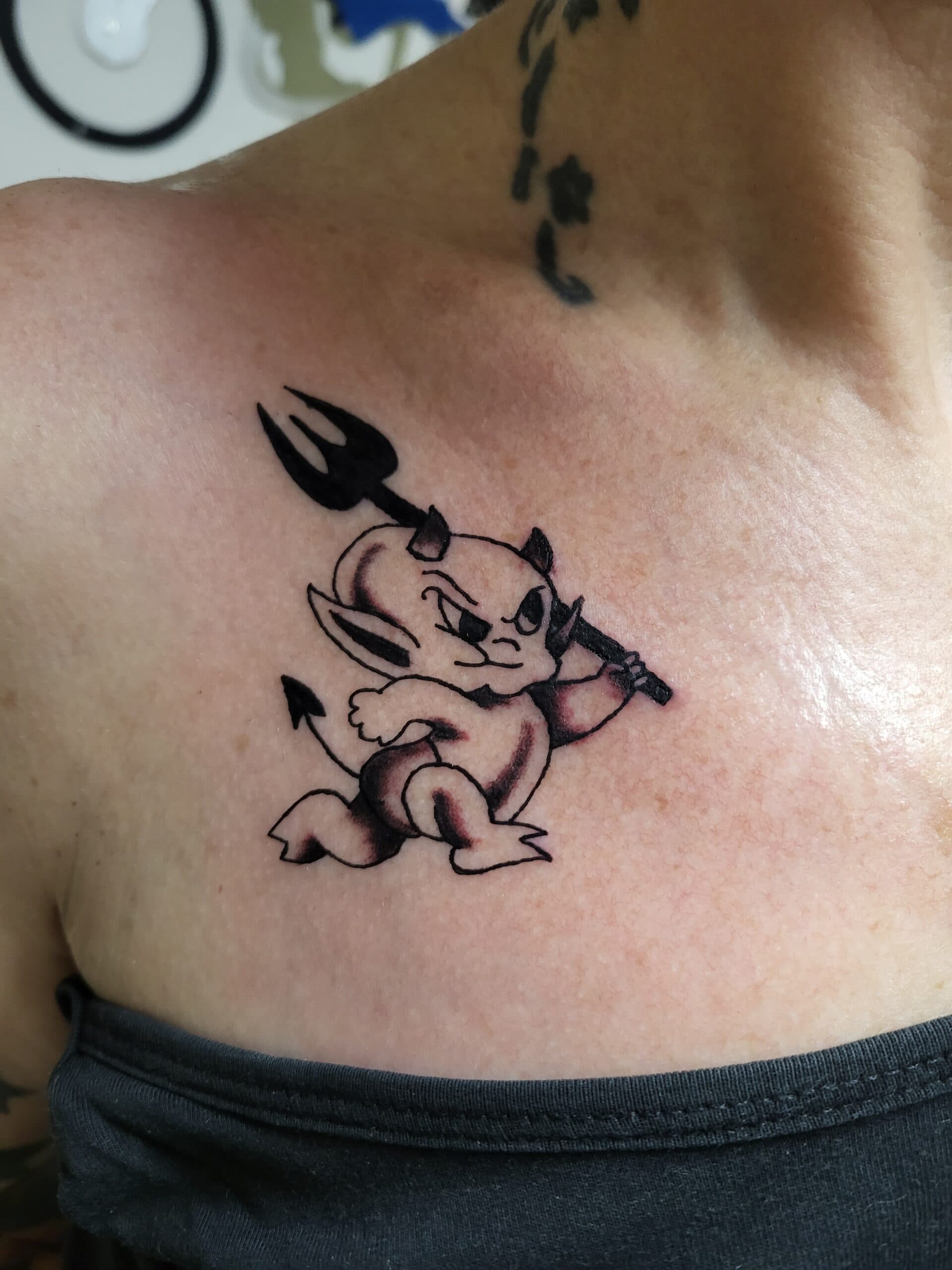 Kleine duivel met drietand op de borst.