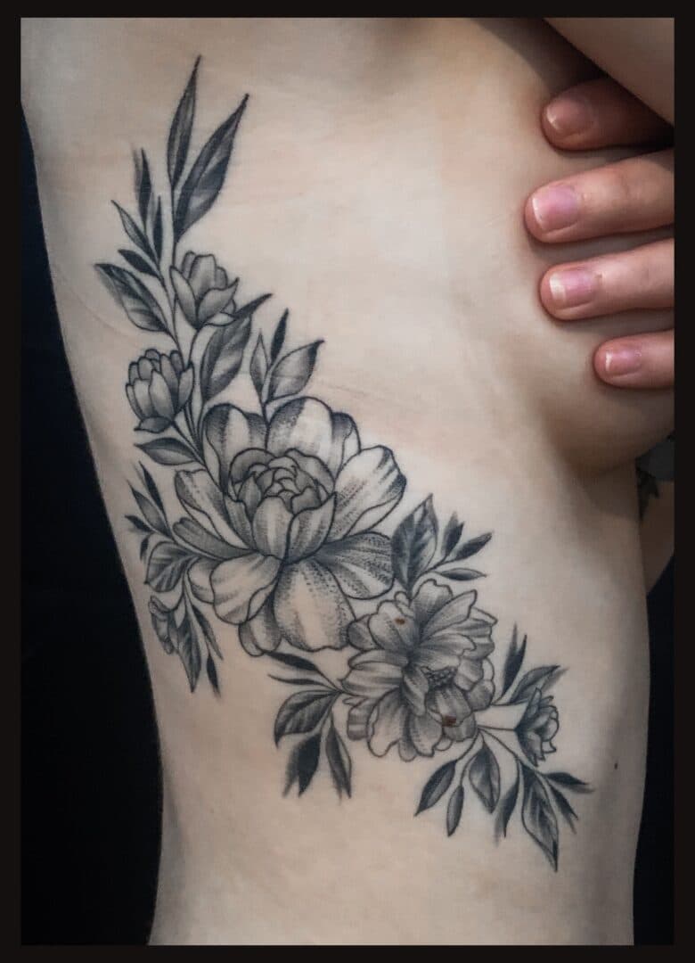 Elegante zwart-wit bloemen tattoo op de ribben.