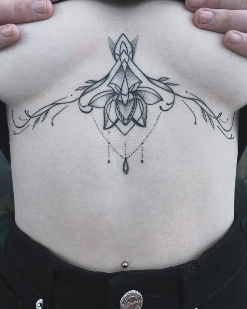 Sierlijke lotus en ornamenten onderborst tattoo.