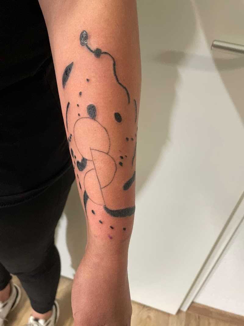 Abstracte zwarte lijnen en stippen op onderarm.