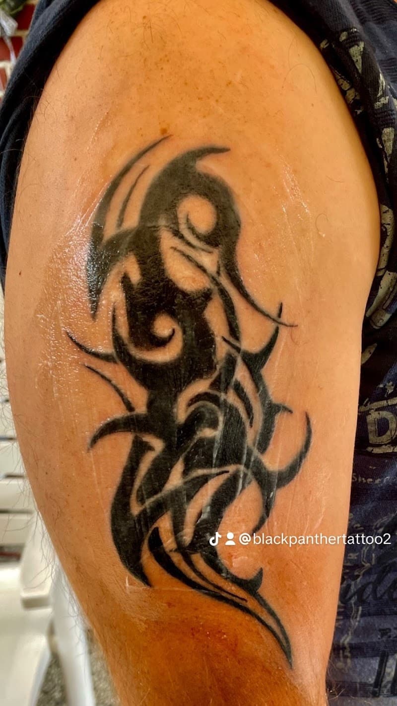 Zwarte tribal tattoo met abstracte vormen op de bovenarm.