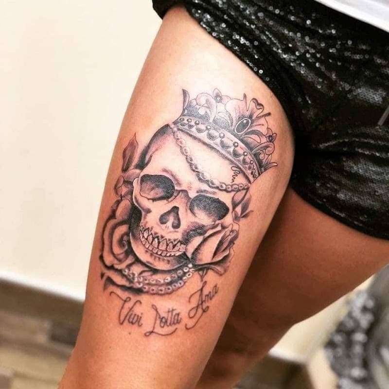Zwart-wit schedel met kroon, rozen en tekst op bovenbeen.