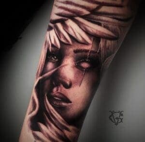 Realistisch portret van een vrouw met veren en een wit oog op de onderarm.