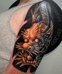 Gedetailleerde Japanse drakenkop tattoo op bovenarm in kleur.