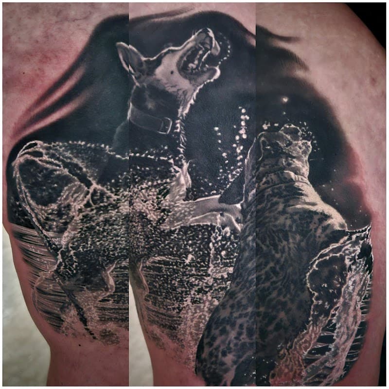 Realistische zwart-wit tattoo van twee spelende honden in water.