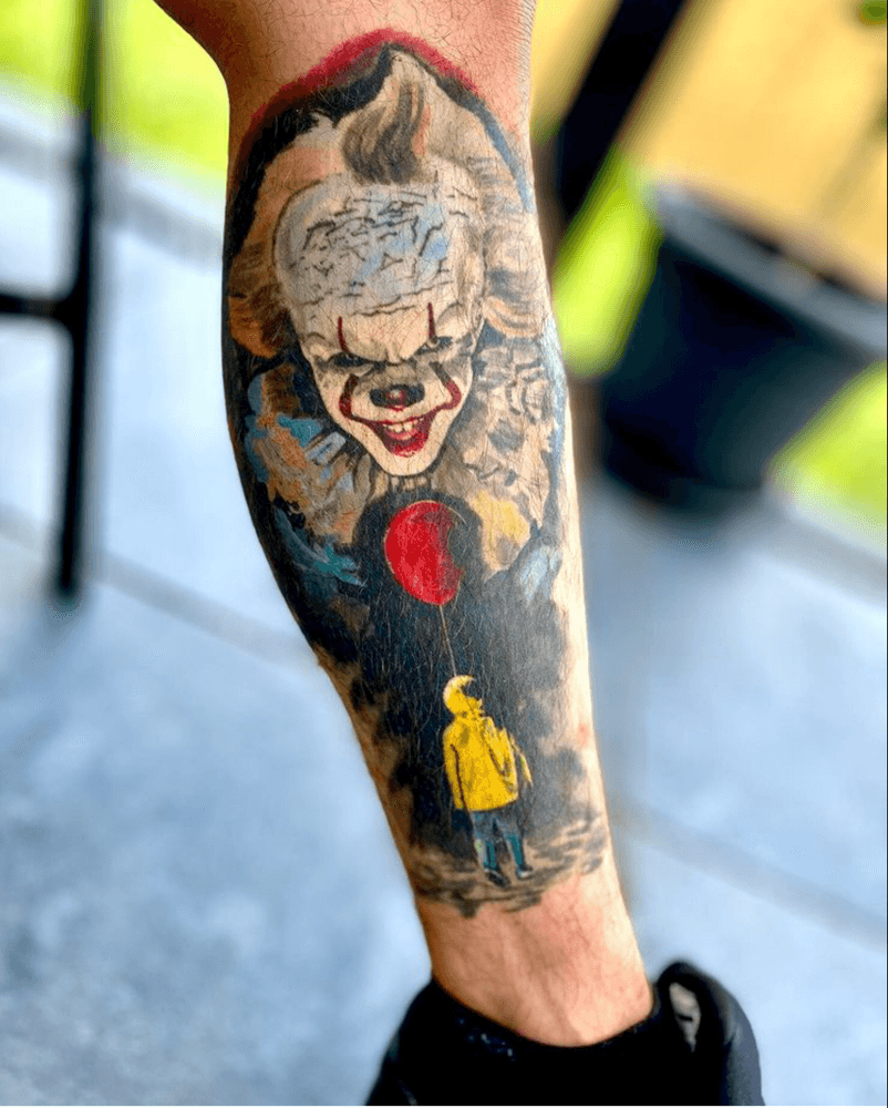 Realistische Pennywise en Georgie met rode ballon tattoo op onderbeen.