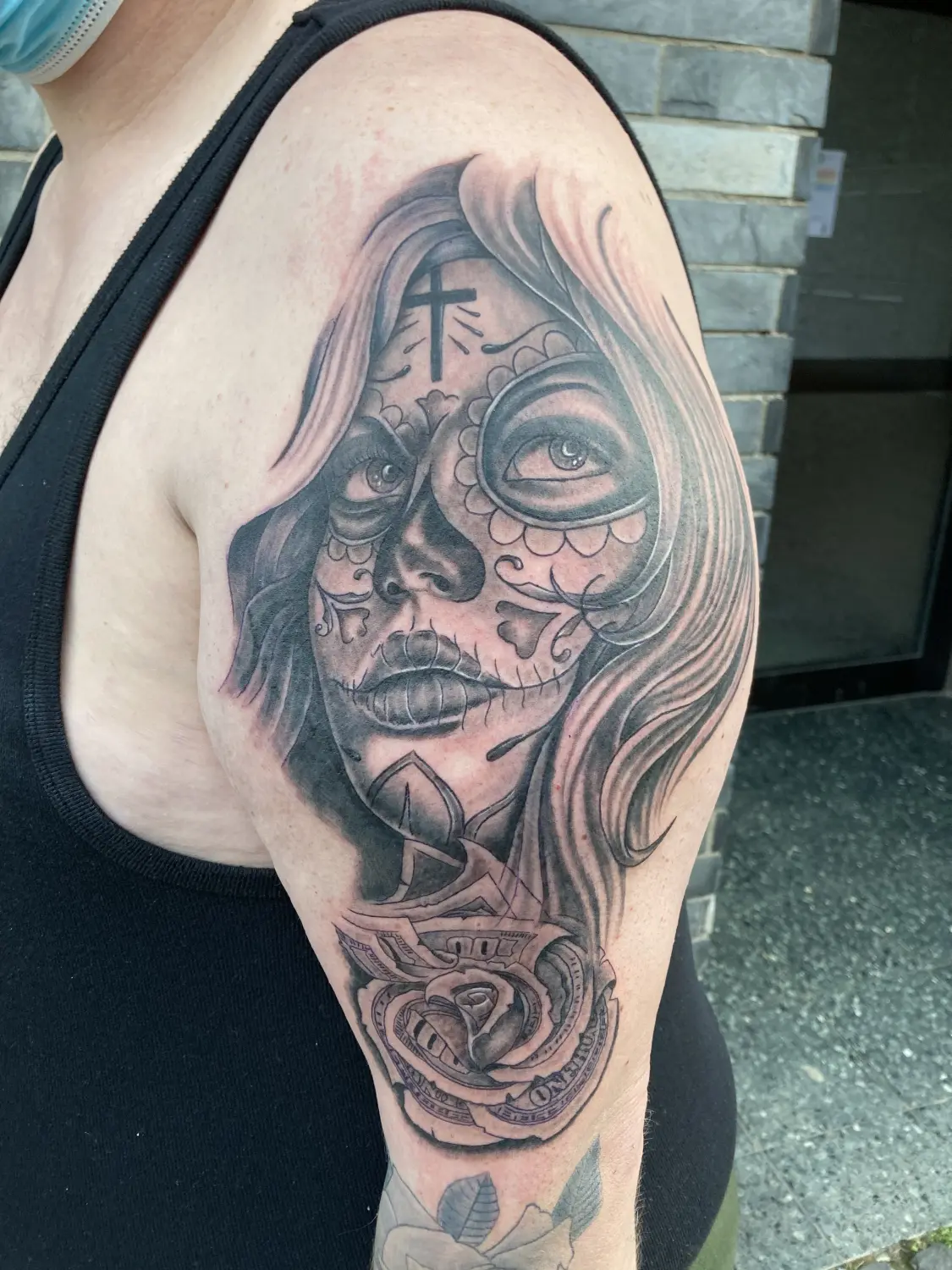 Chicano stijl tattoo van een vrouw met suikerschedel make-up en een roos van geld.