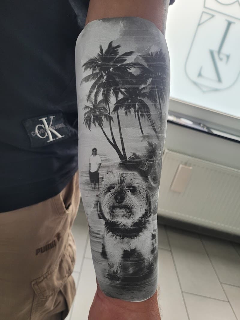 Realistische tattoo van een hond en persoon op een strand met palmbomen.