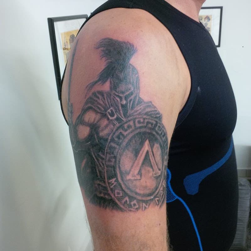 Zwart-wit Spartaanse krijger met schild en zwaard op bovenarm.