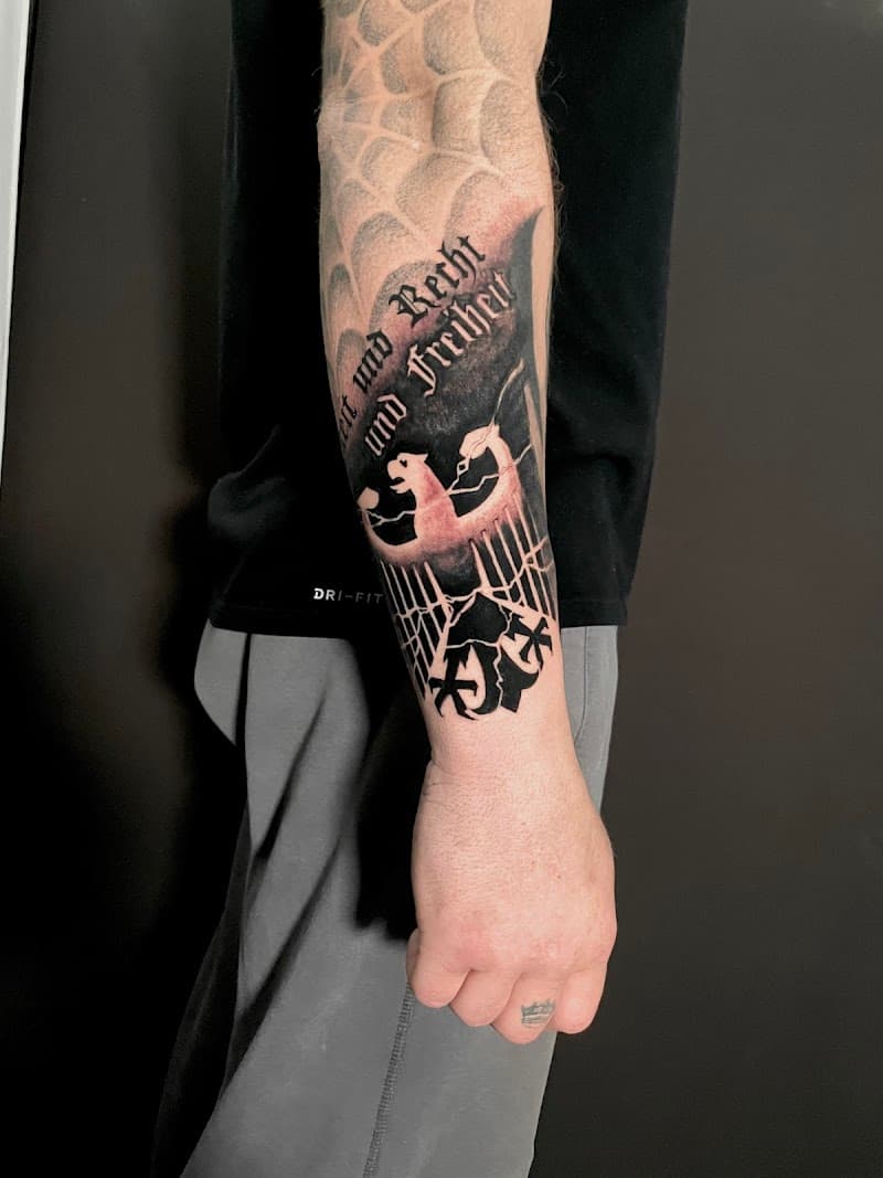 Blackwork adelaar met 'Einigkeit und Recht und Freiheit' tekst op onderarm.