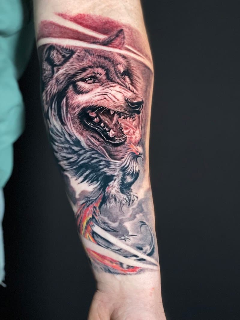 Realistische wolf met feniks en rode accenten op onderarm.
