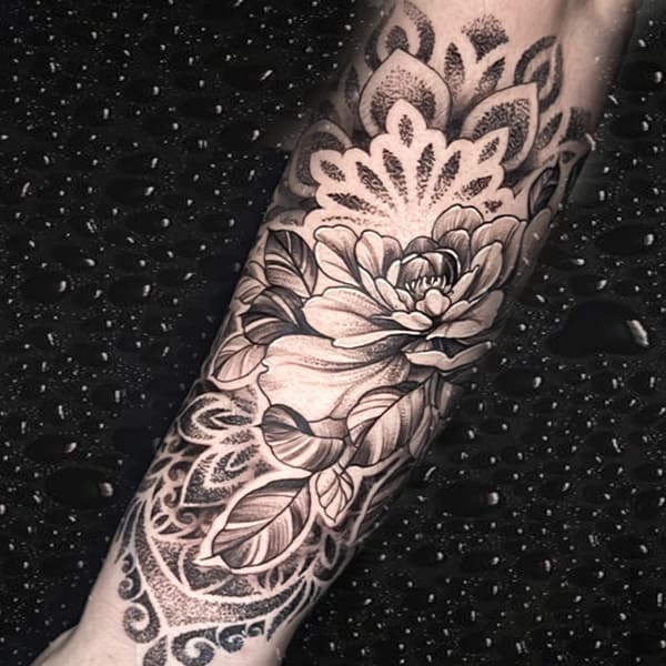 Zwart-wit bloem en mandala half-sleeve tattoo op onderarm.