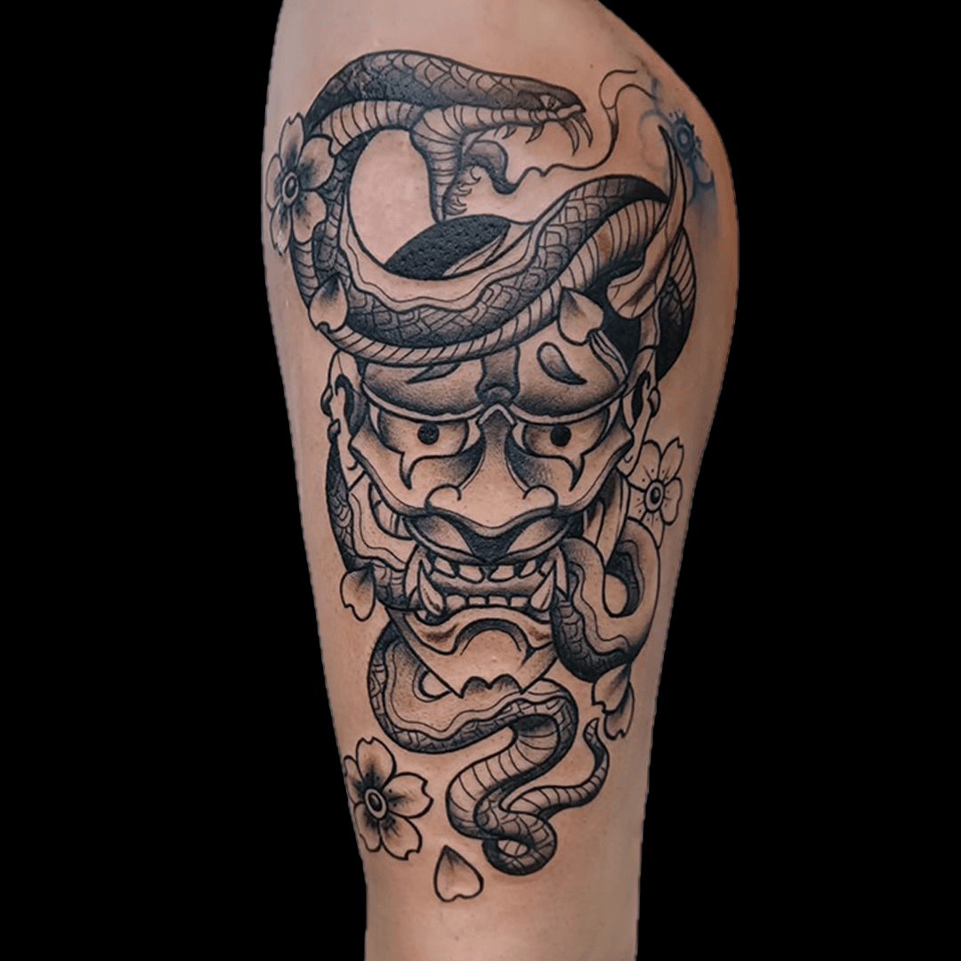 Zwart-wit tattoo van Hannya masker met slang en bloesem op bovenbeen.