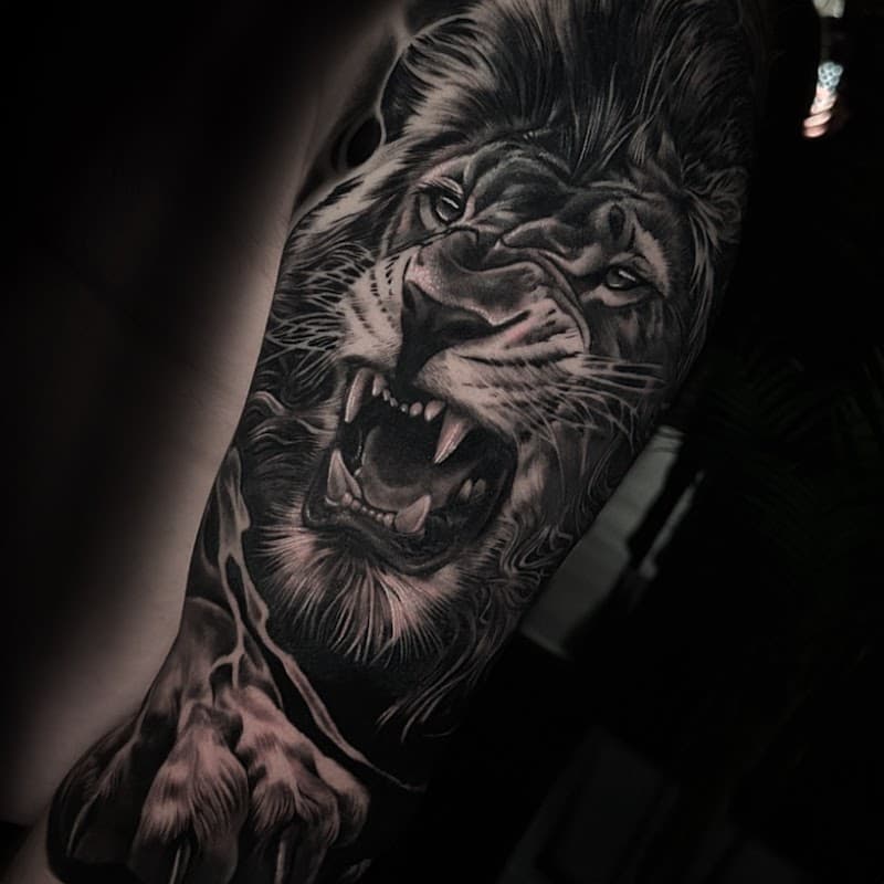 Realistische brullende leeuw tattoo op de bovenarm.