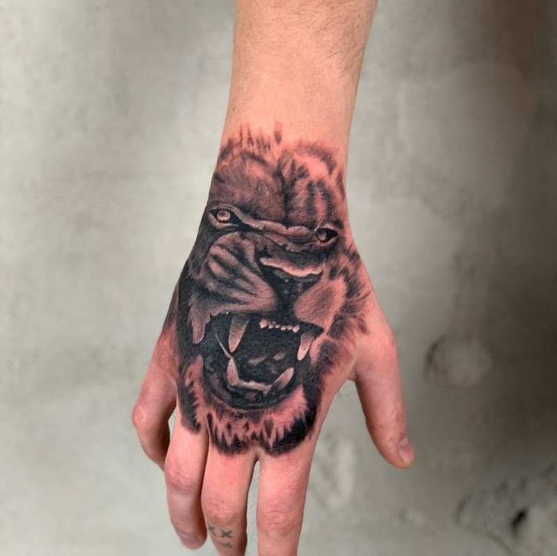 Realistische brullende leeuwenkop tattoo op de hand.