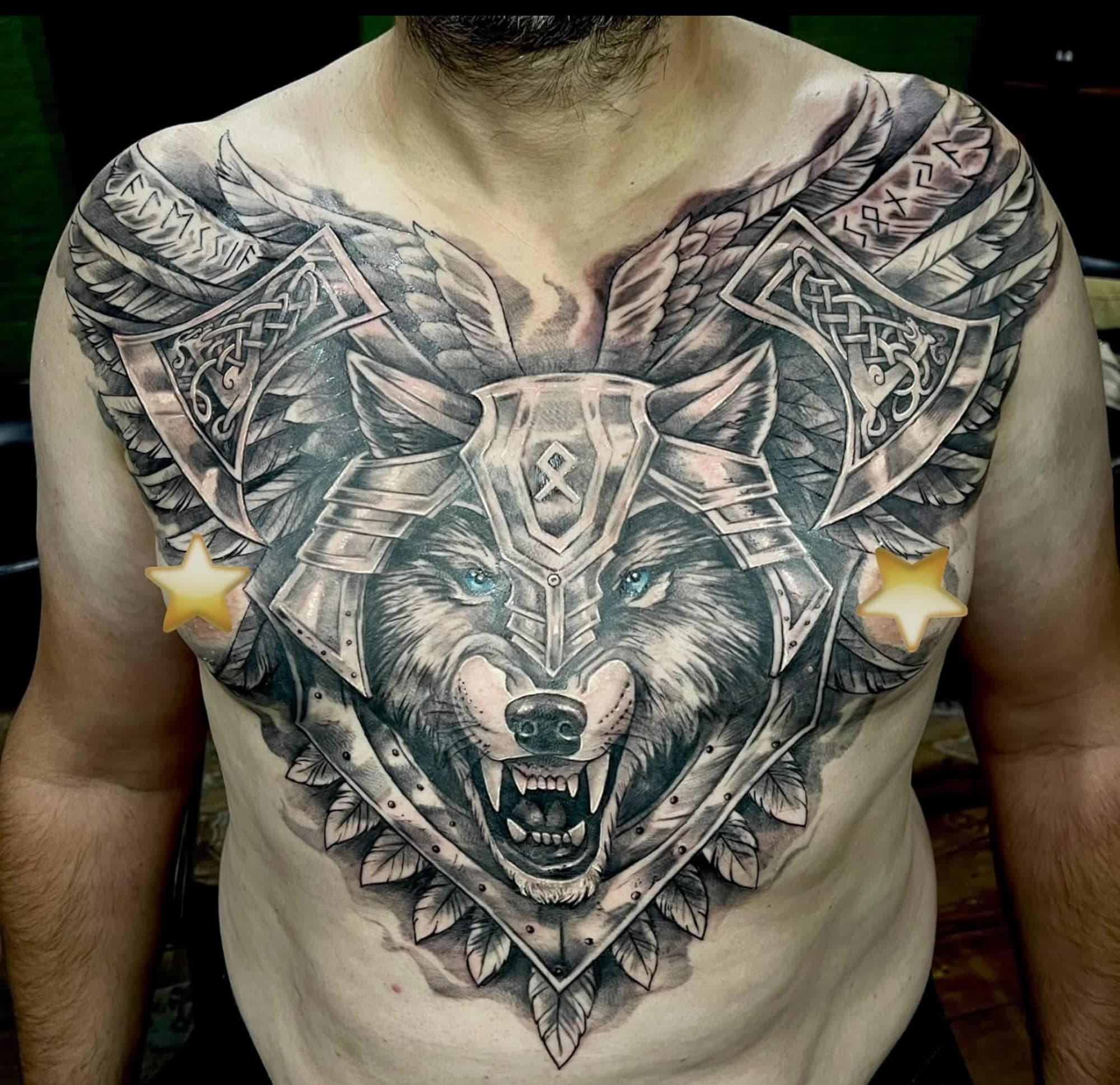 Grote borsttattoo van een wolf in harnas met bijlen en vleugels.
