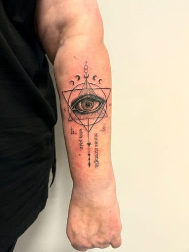 Geometrisch oog met maanfasen en tekst 'with pain comes strength' op onderarm.