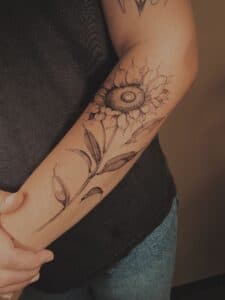 Fineline zonnebloem tattoo op de onderarm.