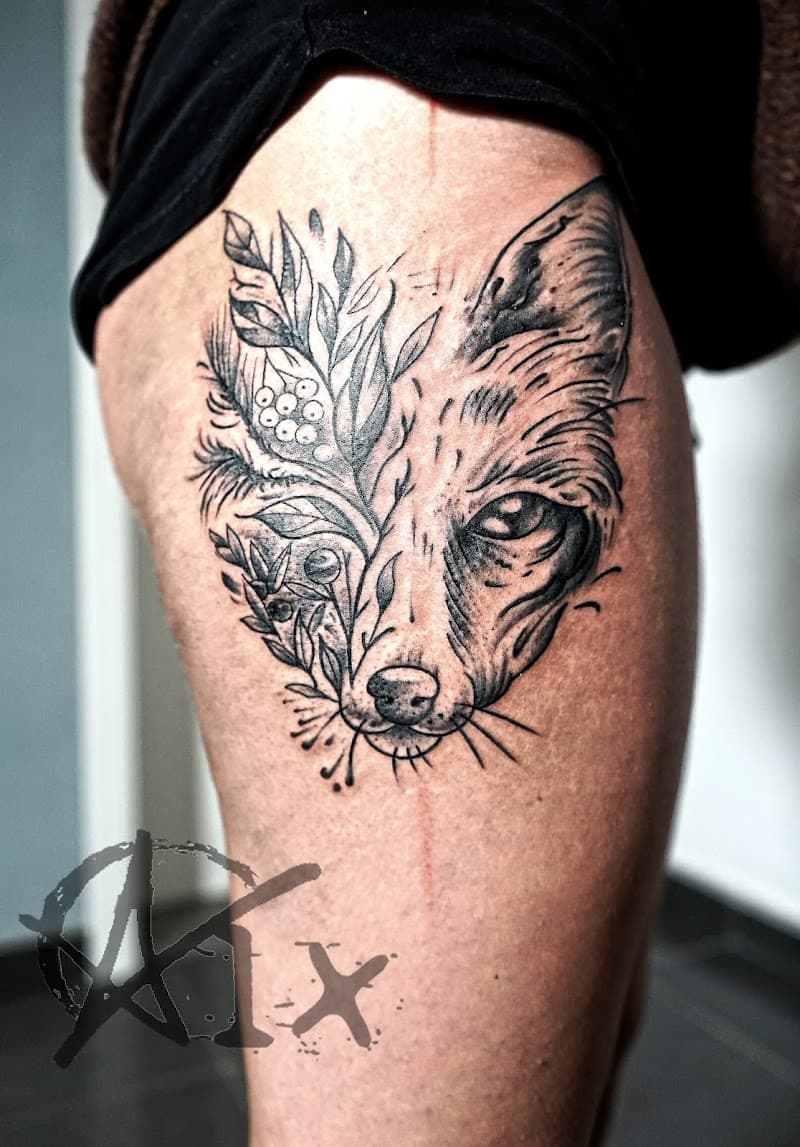 Zwart-wit tattoo van een vossenkop die overgaat in bladeren en bessen.