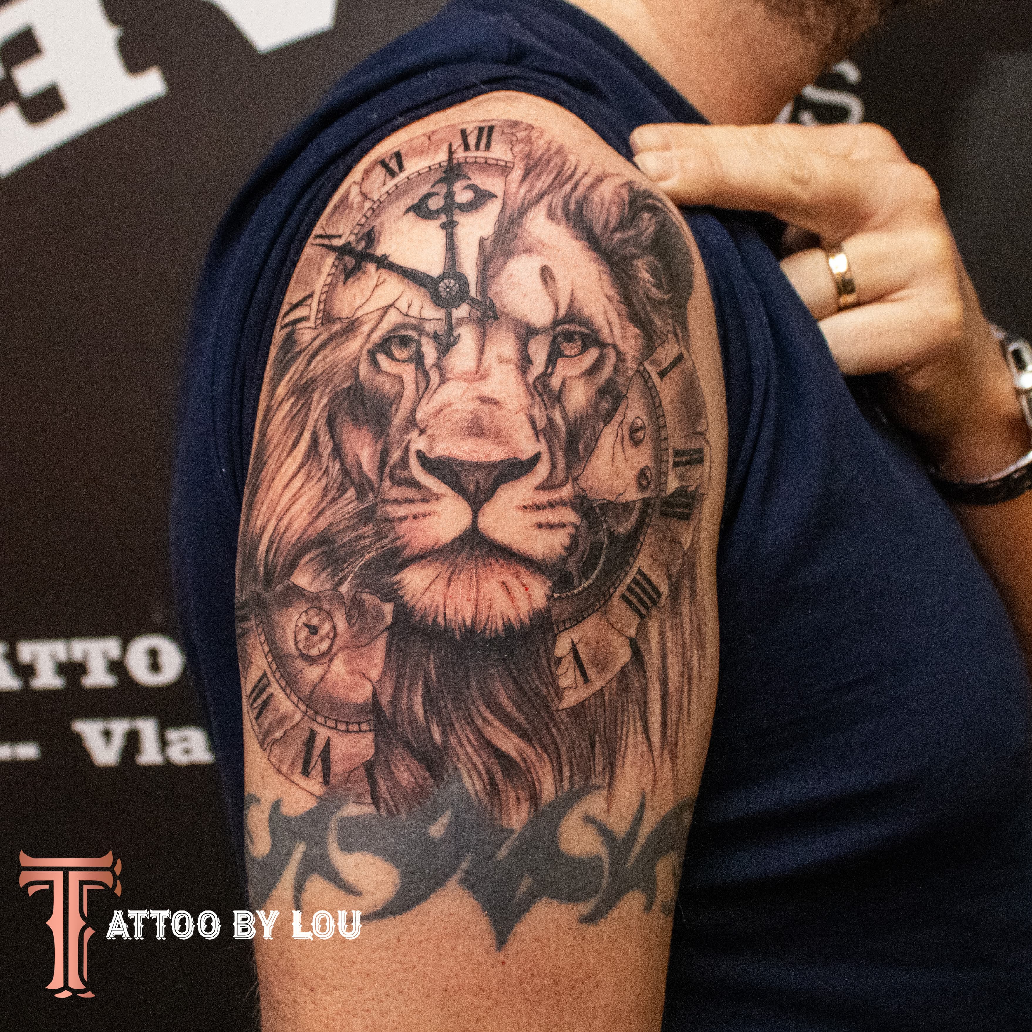 Realistische leeuwenkop samengesmolten met een klok op de bovenarm.