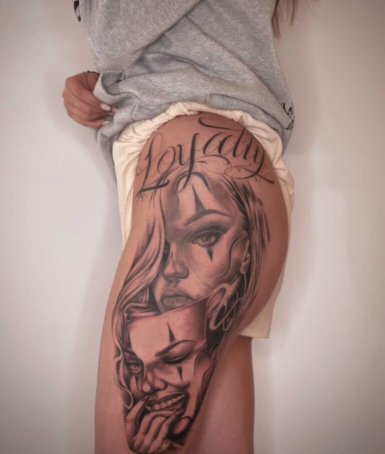 Grote Chicano tattoo op bovenbeen: vrouw, clownmasker en 'Loyalty' tekst.