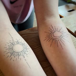 Twee fineline tattoos van een zon en een maan op onderarmen.