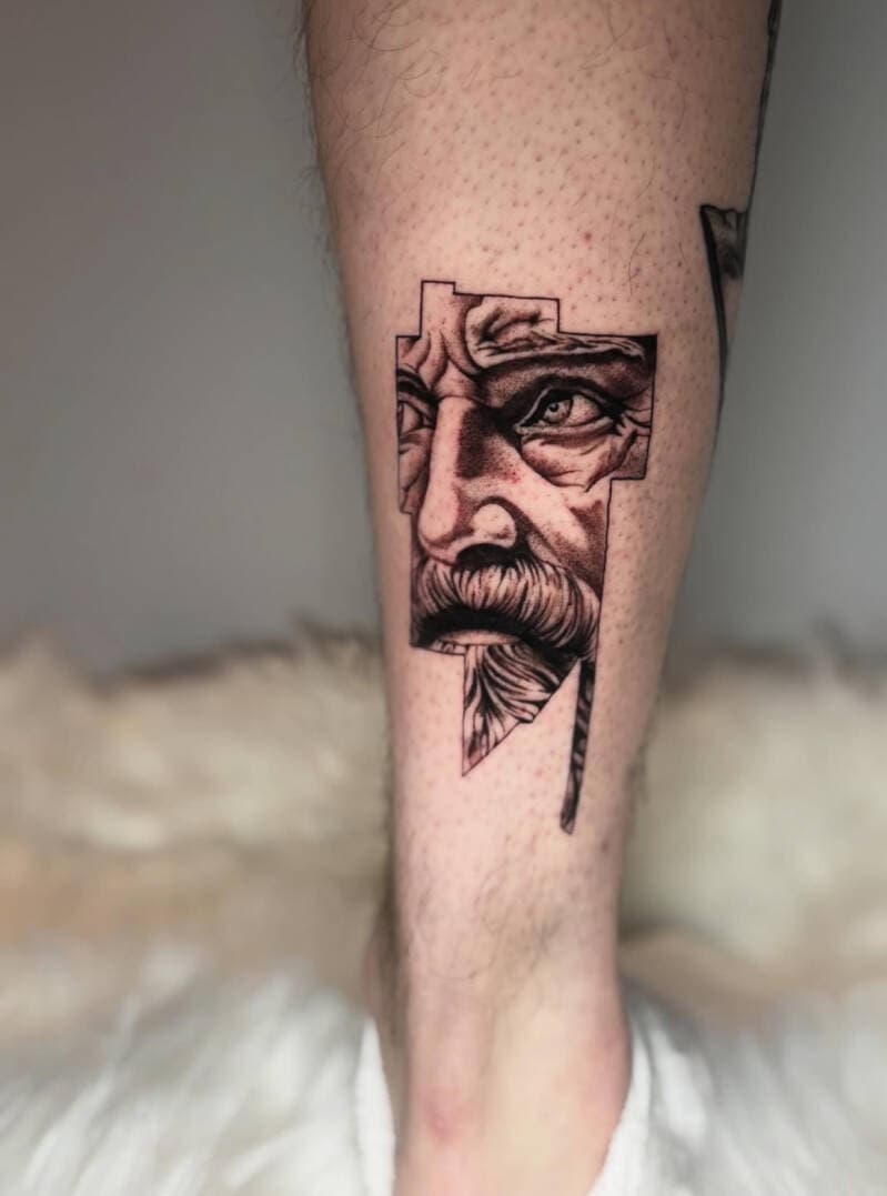 Realistisch portret van een man met baard in een geometrisch kader op het onderbeen.