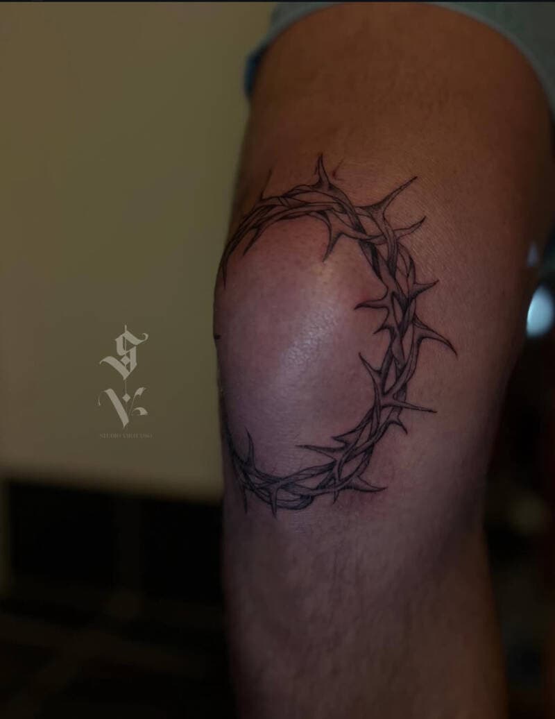 Gedetailleerde doornenkroon tattoo rondom de knie.