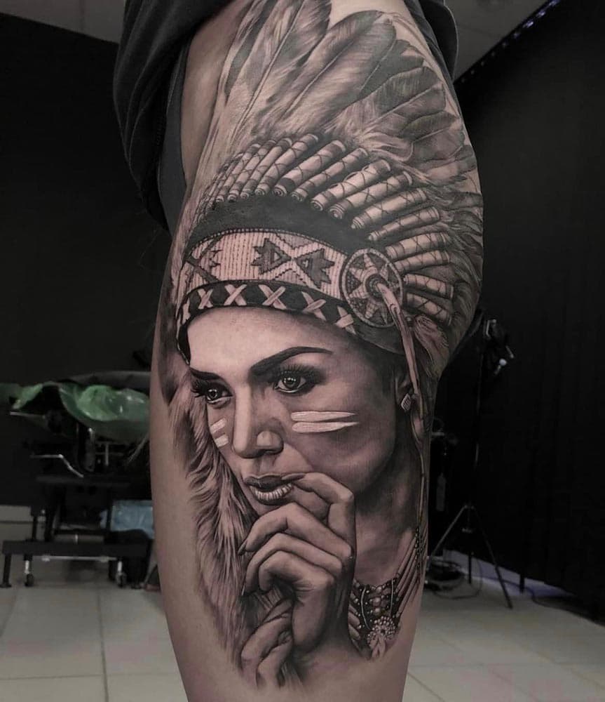 Realistisch portret van een vrouw met indianentooi op het bovenbeen.