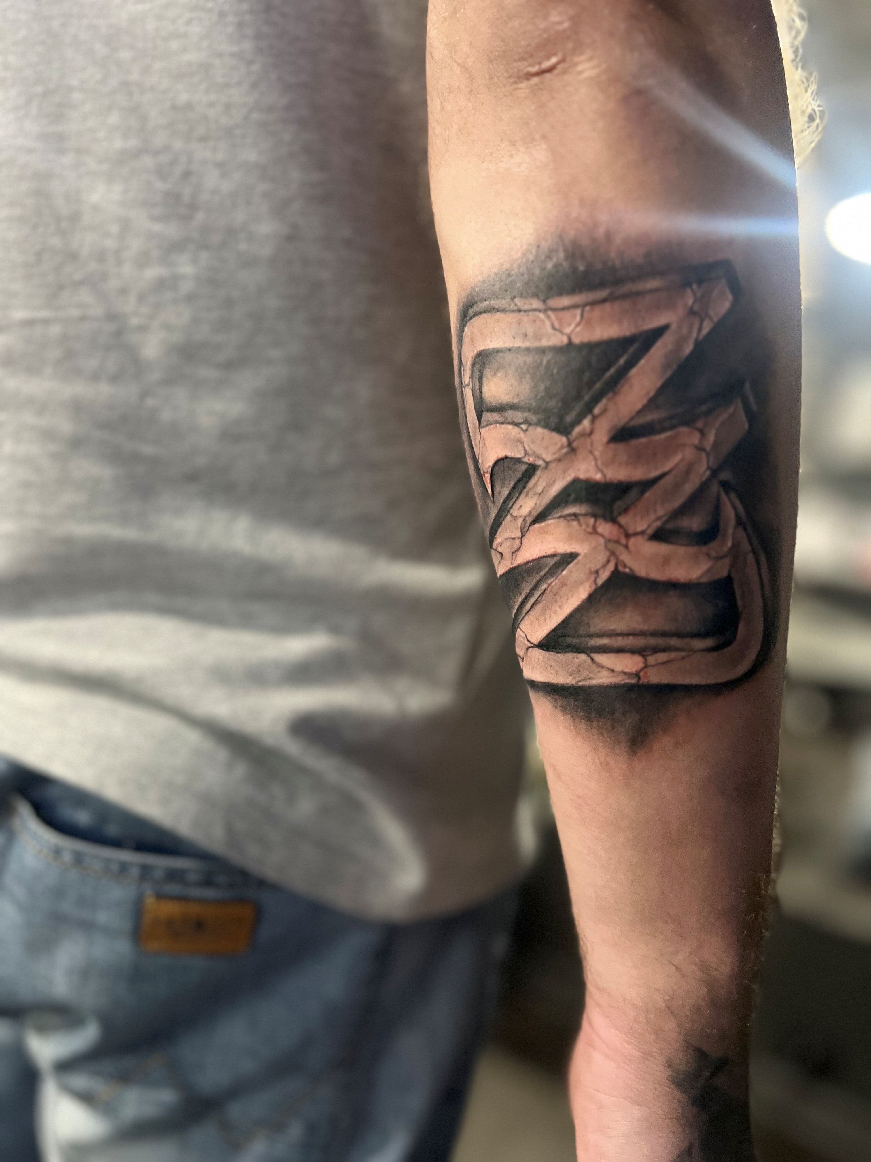 Realistische stenen 'Z' letter tattoo op de onderarm.