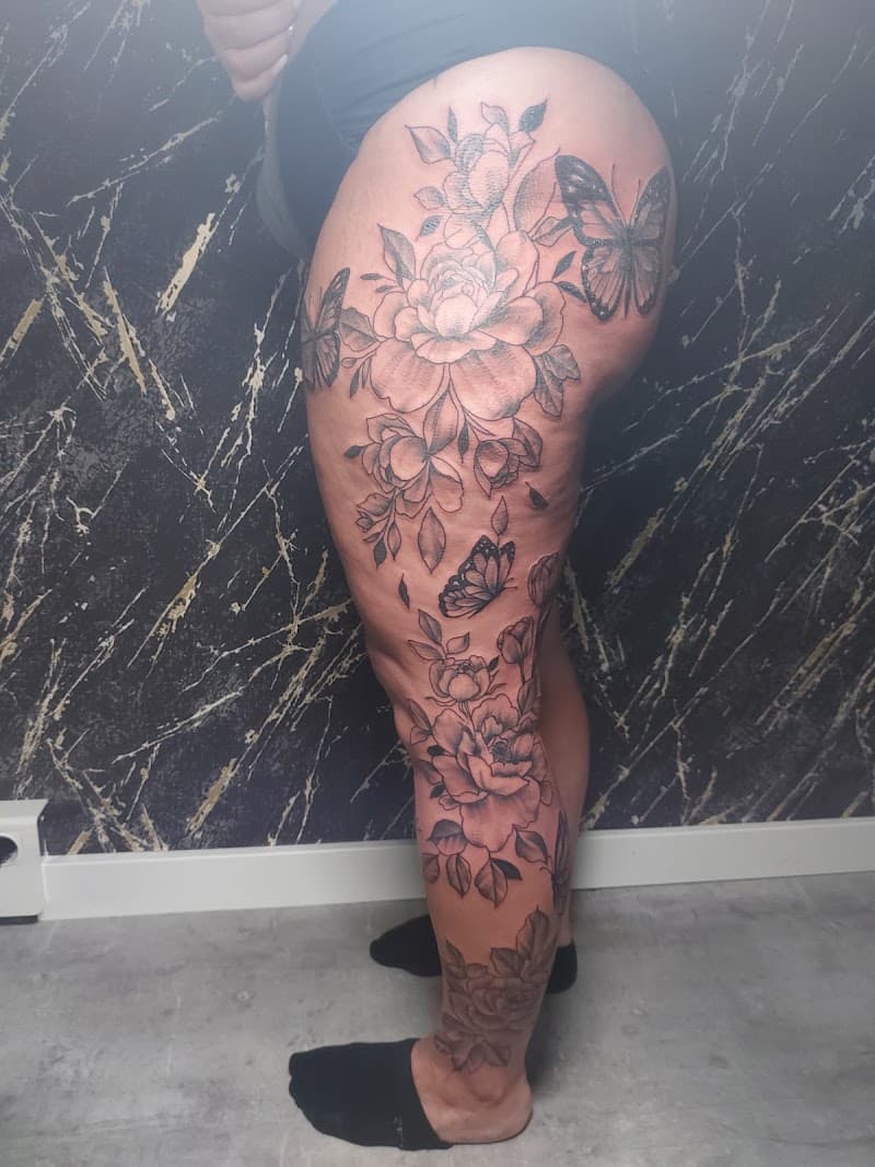 Grote zwart-wit tattoo van pioenen en vlinders op het hele been.