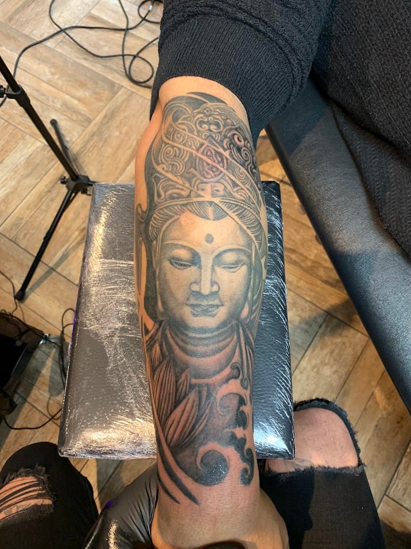 Grote zwart-wit Boeddha tattoo op onderarm met lotus en golven.