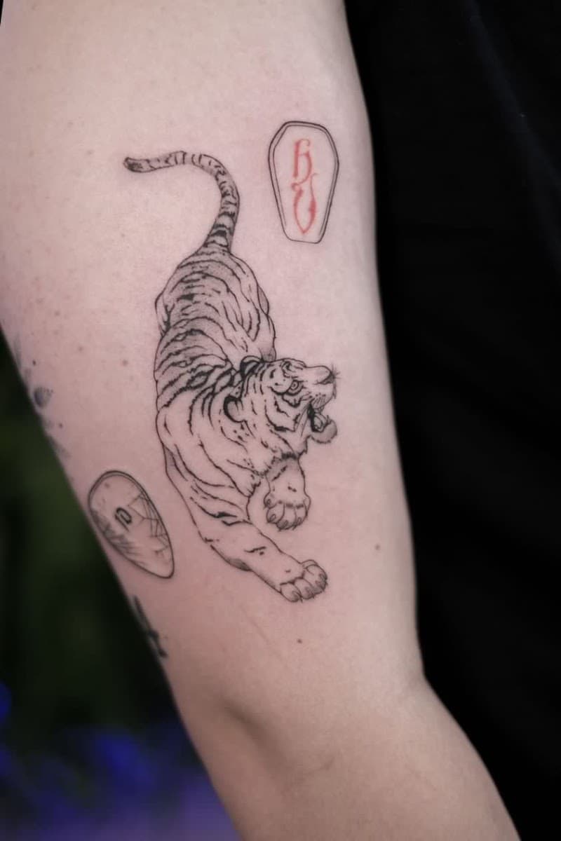 Illustratieve tijger met twee kleine symbolen op bovenarm.