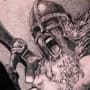 Realistische zwart-wit tattoo van een schreeuwende Viking krijger met helm en bijl.