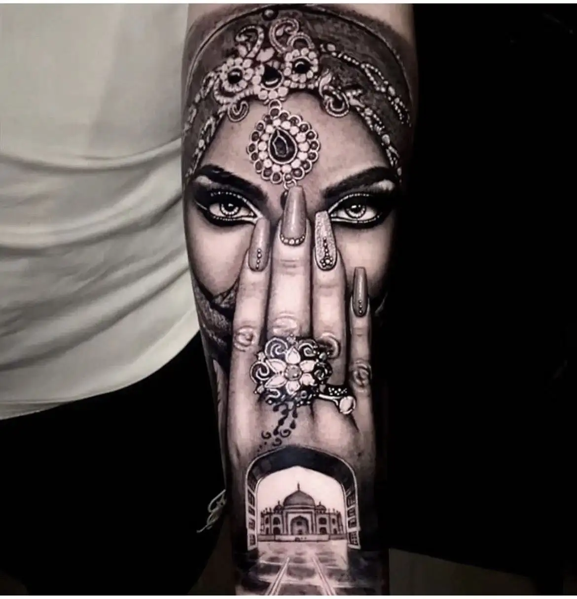 Realistische tattoo van vrouw met sieraden, hand voor gezicht en Taj Mahal.