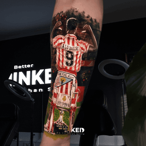 Realistische tattoo van voetballer met trofee op onderbeen.