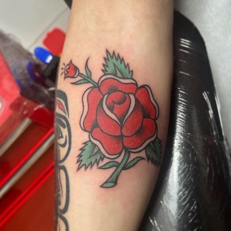 Traditionele rode roos tattoo op de onderarm.