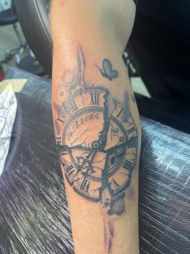 Gebroken klok met datum 04.12.2024 en vlinder op onderbeen.