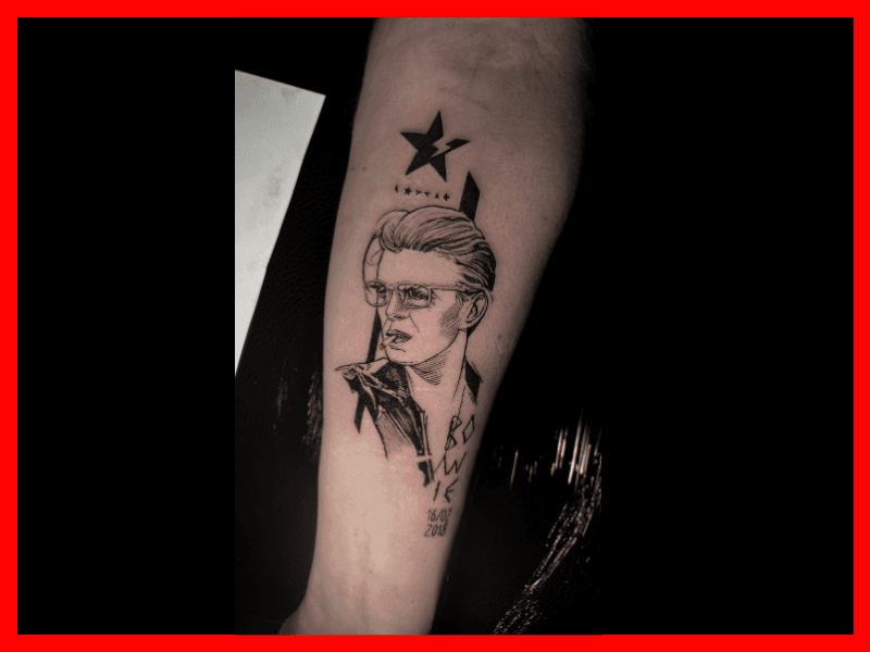 Blackwork portret van David Bowie met ster en tekst op onderarm.