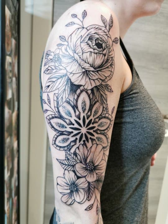 Zwart-wit half-sleeve met bloemen en mandala op bovenarm.