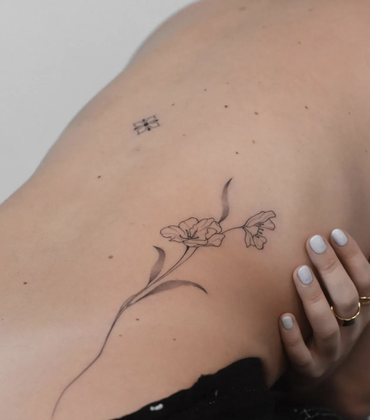 Fineline bloementak en klein geometrisch symbool op de rug.