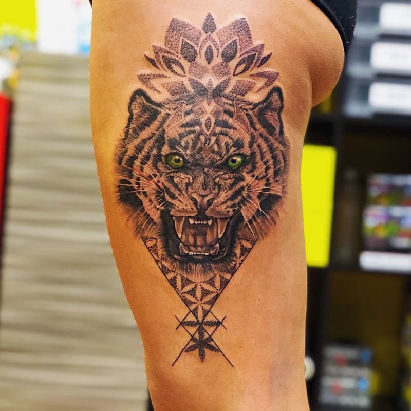 Realistische tijger met groene ogen en geometrische mandala op bovenbeen.