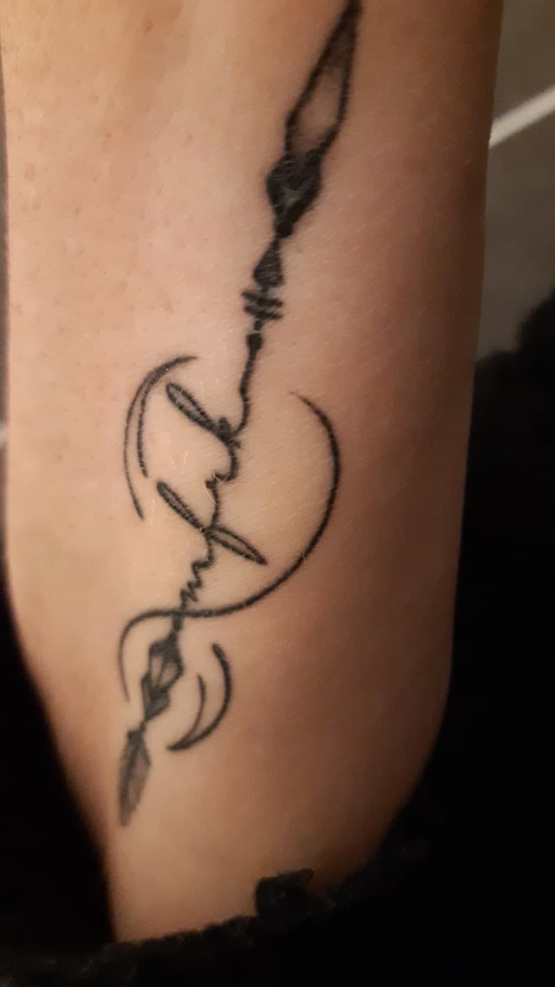 Blackwork pijl tattoo met het woord 'faith' verwerkt in de schacht op de onderarm.