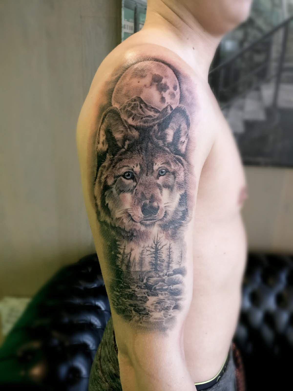 Realistische wolf met maan en boslandschap op bovenarm.