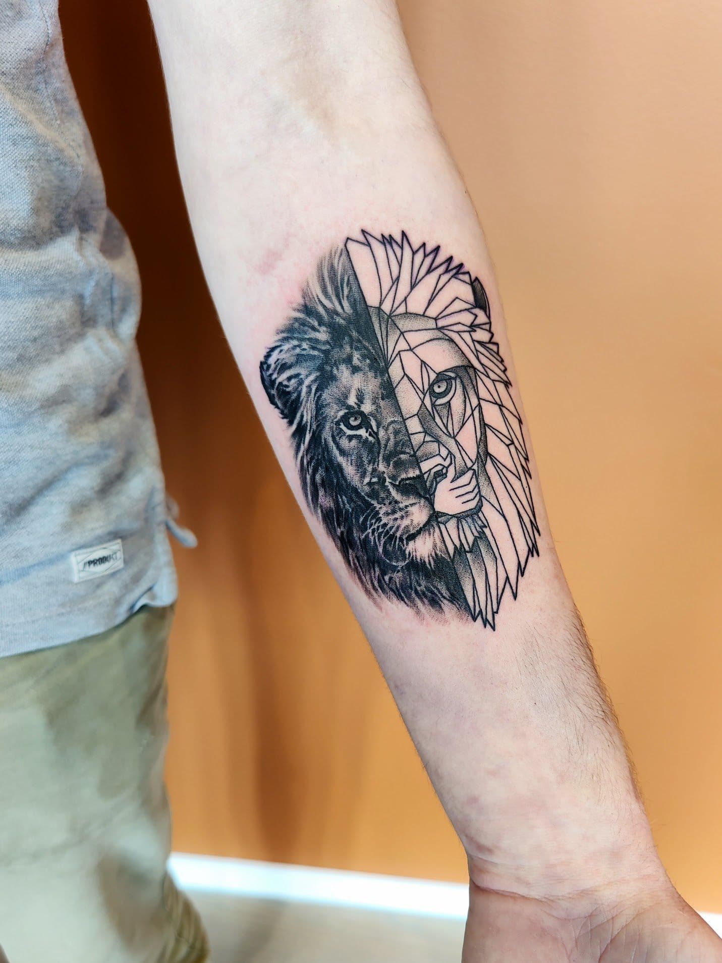 Halve realistische, halve geometrische leeuwenkop op onderarm.