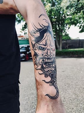 Zwart-wit Japanse Oni masker tattoo op onderarm.